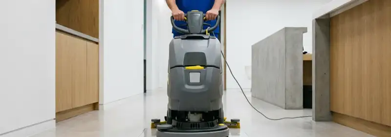 Janitorial staff using a floor scrubber machine to clean a commercial hallway, San Francisco, CA.